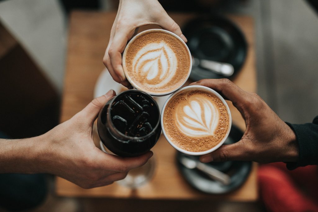 Three hands toasting with coffee