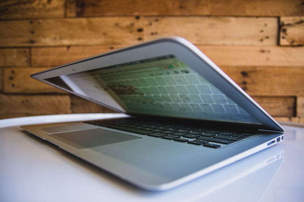 Partially closed laptop on a white surface.