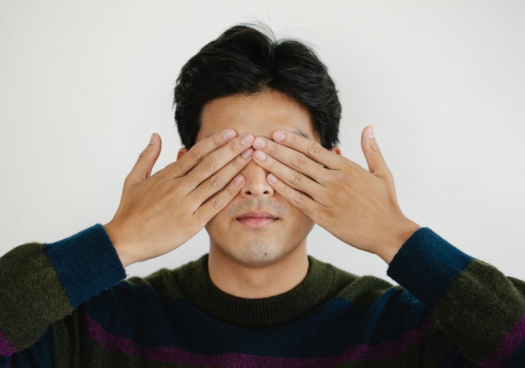 man covering his eyes